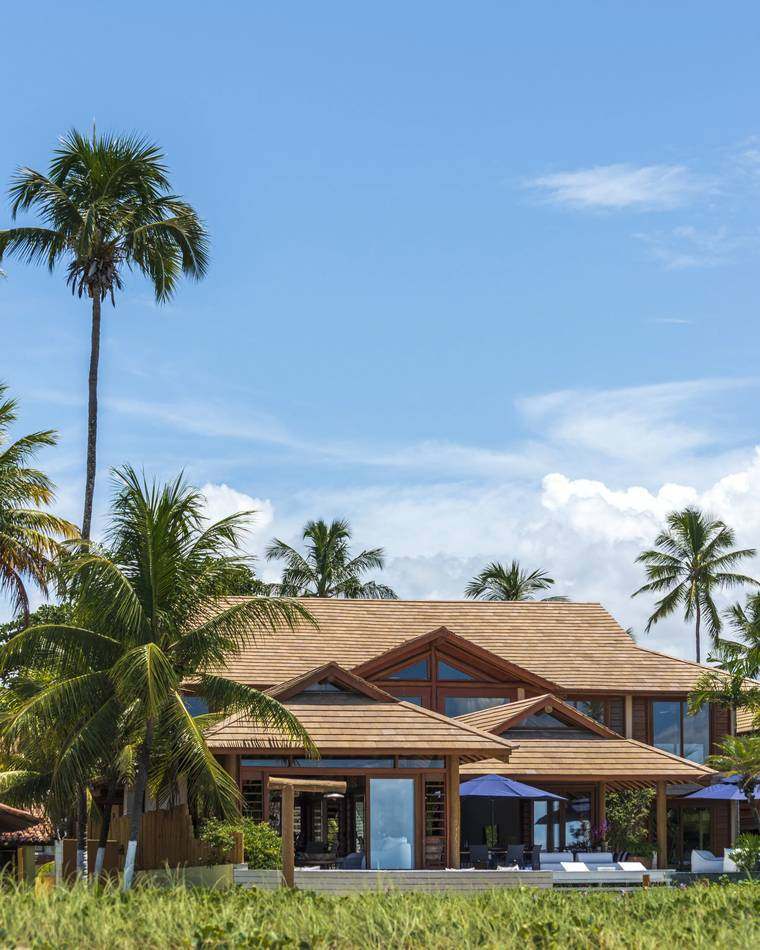 Fachada da Villa Capri vista da praia, entre coqueiros