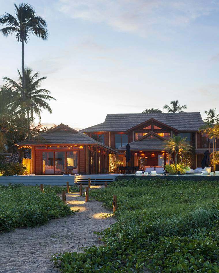 Casa iluminada ao entardecer, vista do caminho de areia