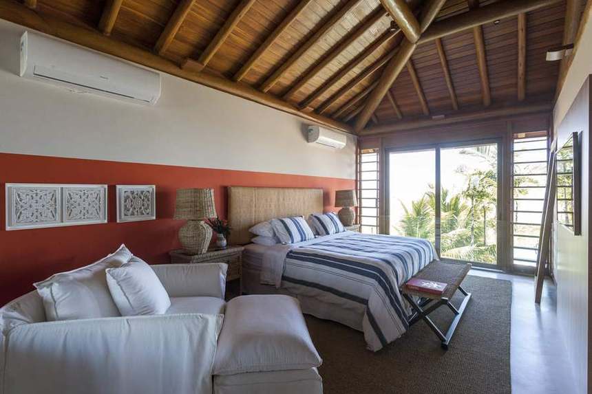 Suíte master com cama king, poltronas e faixa terracota