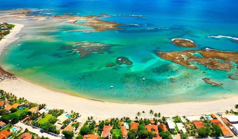 Vista aérea de Serrambi — enseada com piscinas naturais de recife na maré baixa