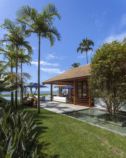 Jardim, deck e espelho d'água entre a casa e o mar
